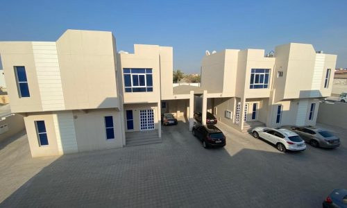 A white building with cars parked in front of it.