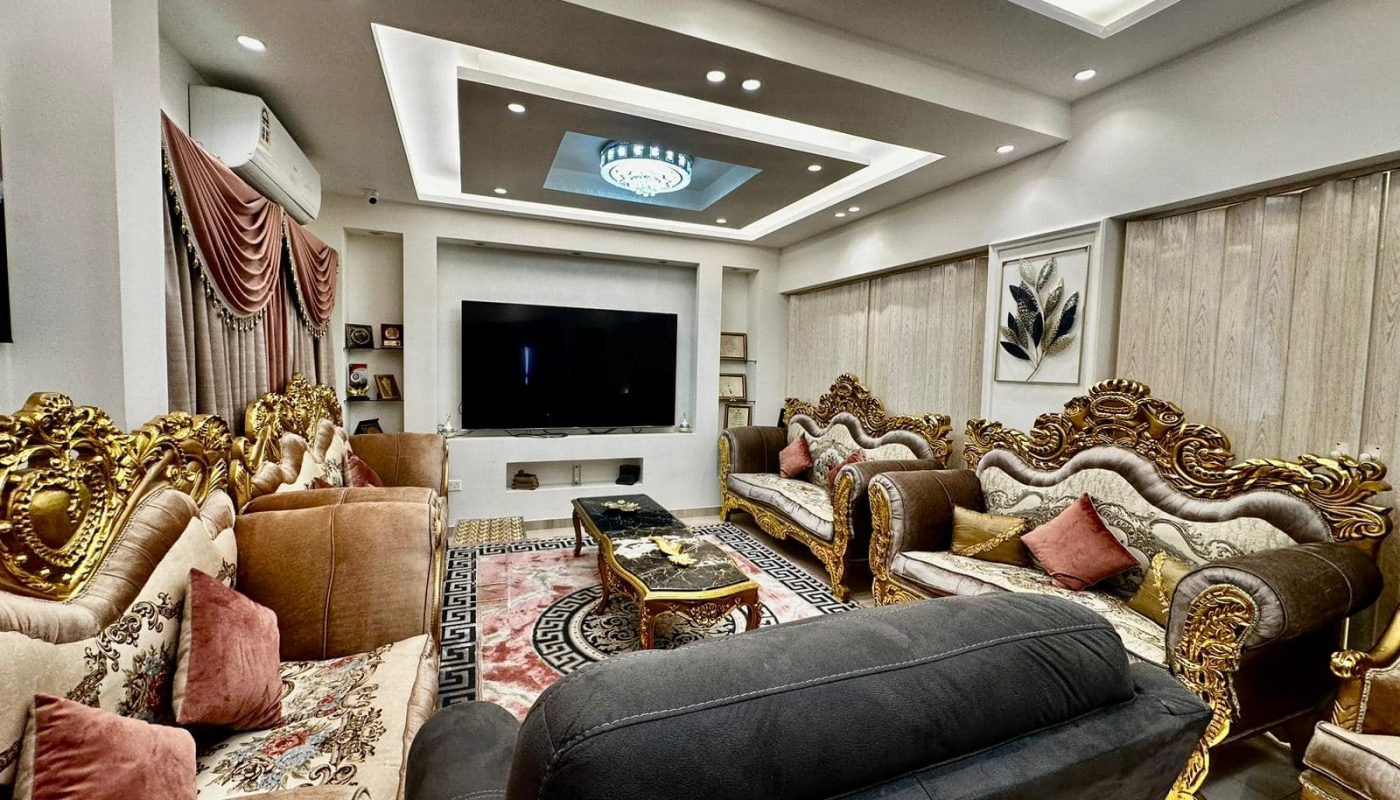 A luxurious living room with gold furniture and a TV in a modern setting.