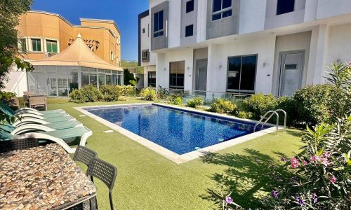 An apartment with a swimming pool in front of it.