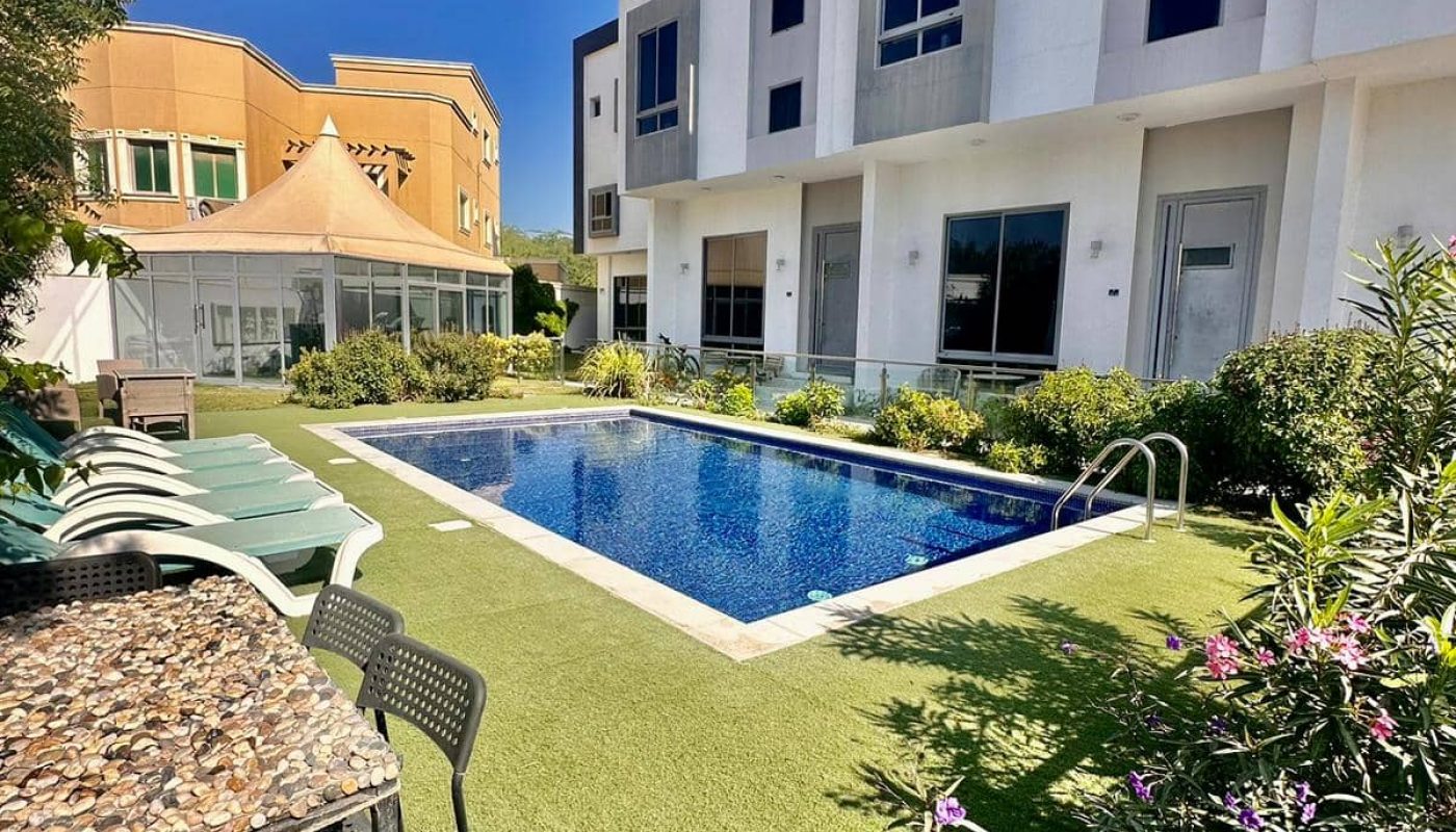 An apartment with a swimming pool in front of it.