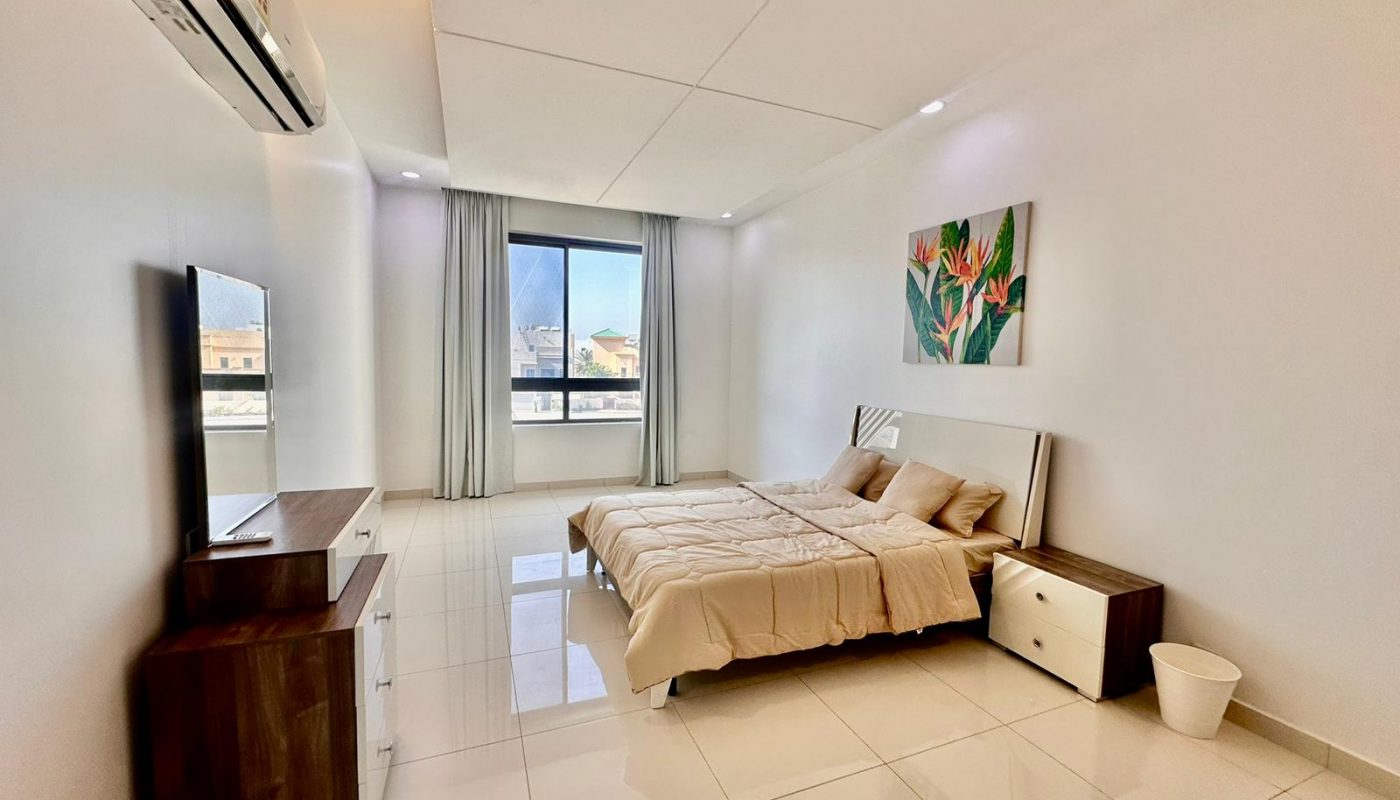 A white bedroom with a bed and a television.