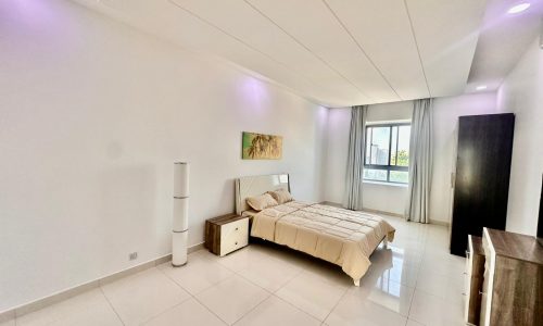 A white bedroom with a bed and a bedside table.