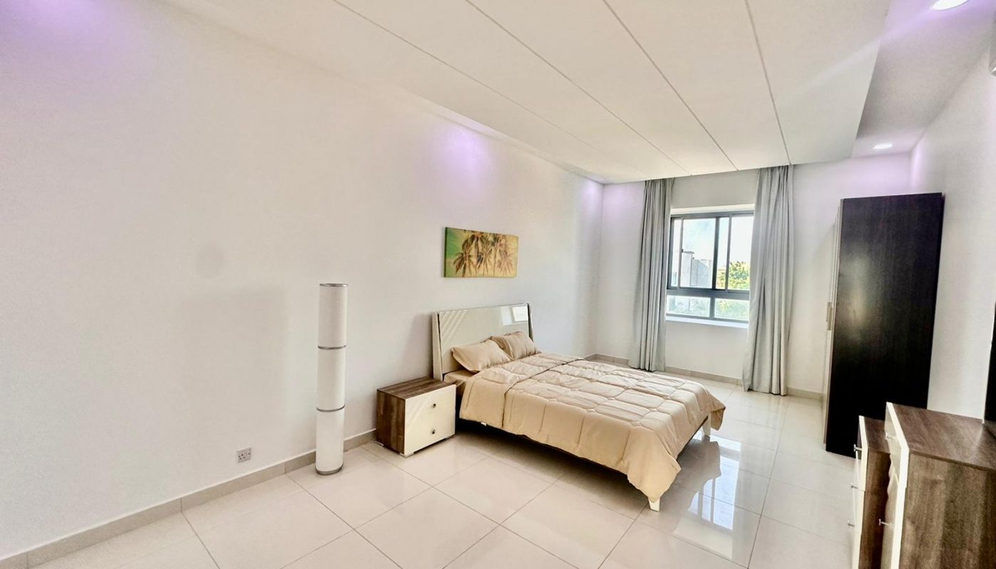 A white bedroom with a bed and a bedside table.