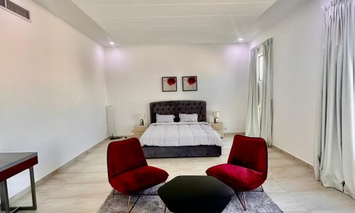 A bedroom with a large bed and red chairs.