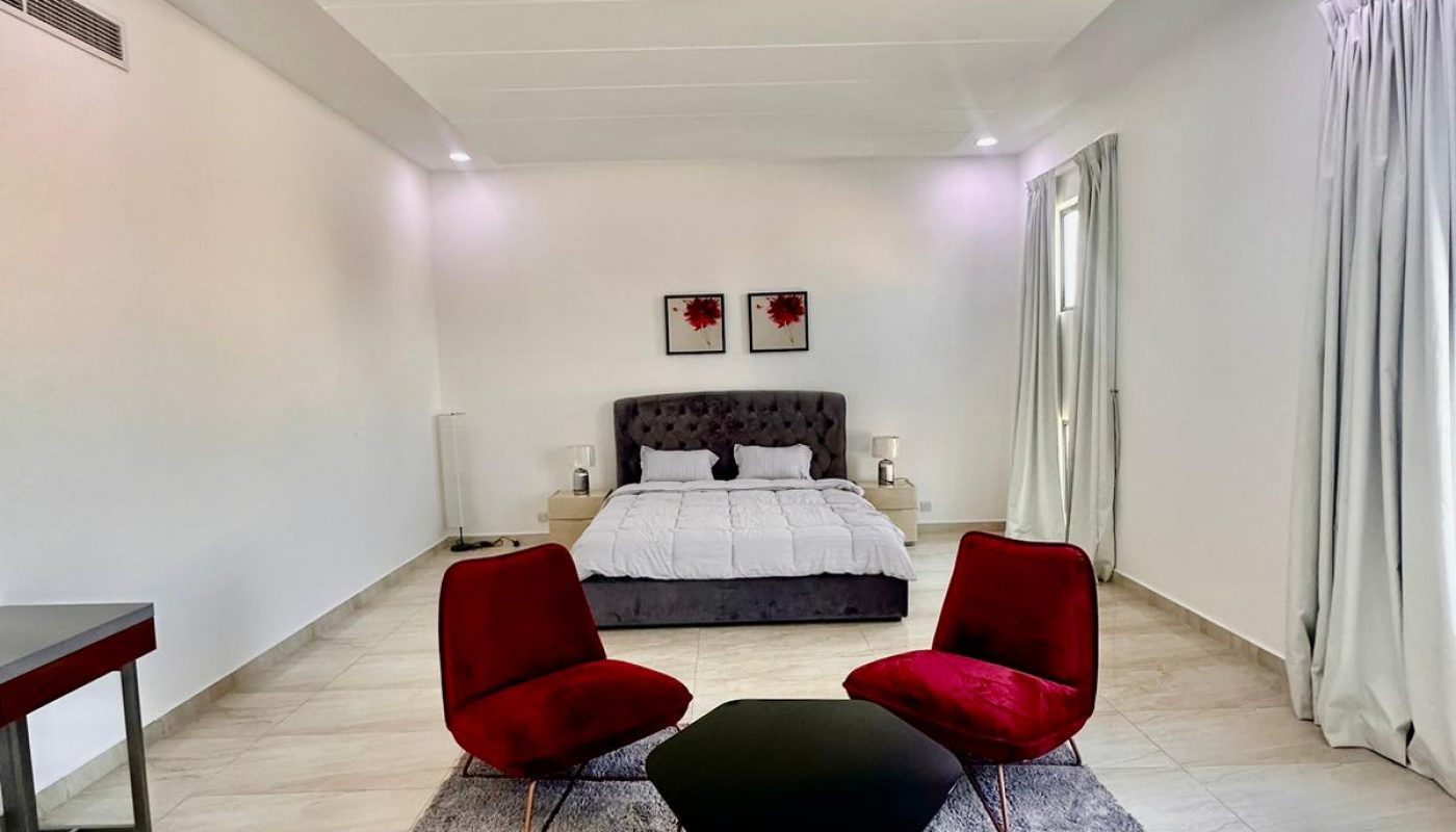 A bedroom with a large bed and red chairs.