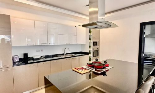 A modern kitchen with black counter tops and stainless steel appliances.