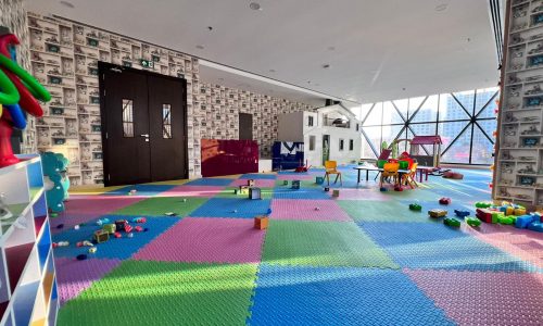 A luxurious residential apartment in JUFFAIR with a children's playroom filled with colorful flooring and toys.