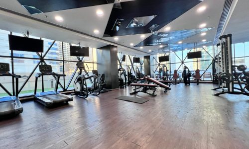 A gym room with large windows and tread machines in JUFFAIR, situated in luxurious residential towers.