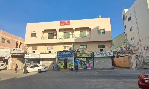 An auto draft building with cars parked in front of it.