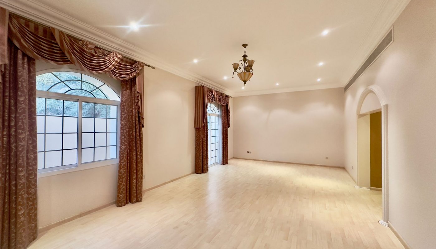 A spacious and semi-furnished large empty room with wooden floors and large windows in Al Janabiyah.