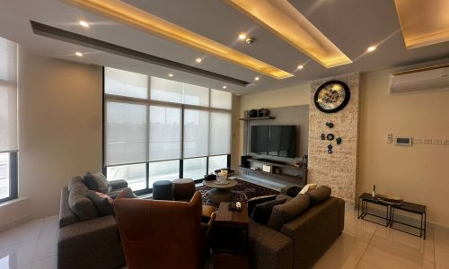 A modern fully-furnished living room in Al Janabiyah with a flat screen TV and a fireplace.