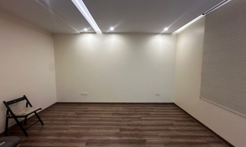 A room with a wooden floor and white walls in a modern, fully-furnished luxury apartment.