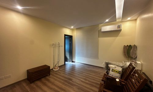 A luxury, fully-furnished apartment featuring 3 bedrooms, with wooden floors and a fan in an empty room.