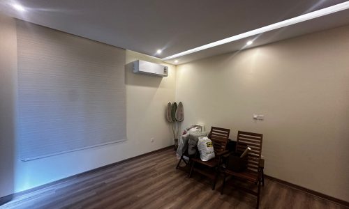 A fully-furnished room with a wooden floor and a fan.