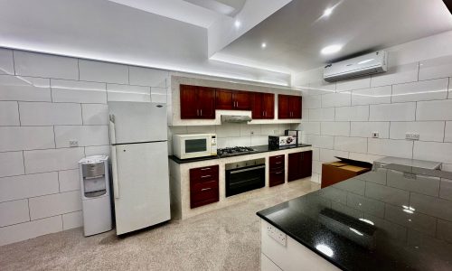 A fully-furnished kitchen with a refrigerator and microwave.