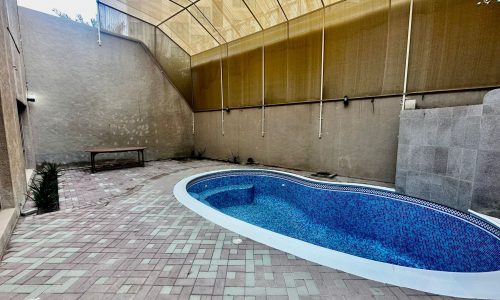 A private pool in a backyard with a shaded area.