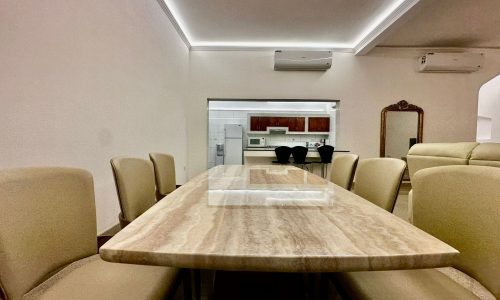 A luxury dining room with a marble table and fully-furnished chairs.