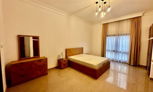 A fully-furnished bedroom with a bed, dresser and mirror.