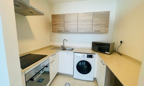 A luxurious 1 BR apartment in Juffair with a small kitchen equipped with a washer and dryer.