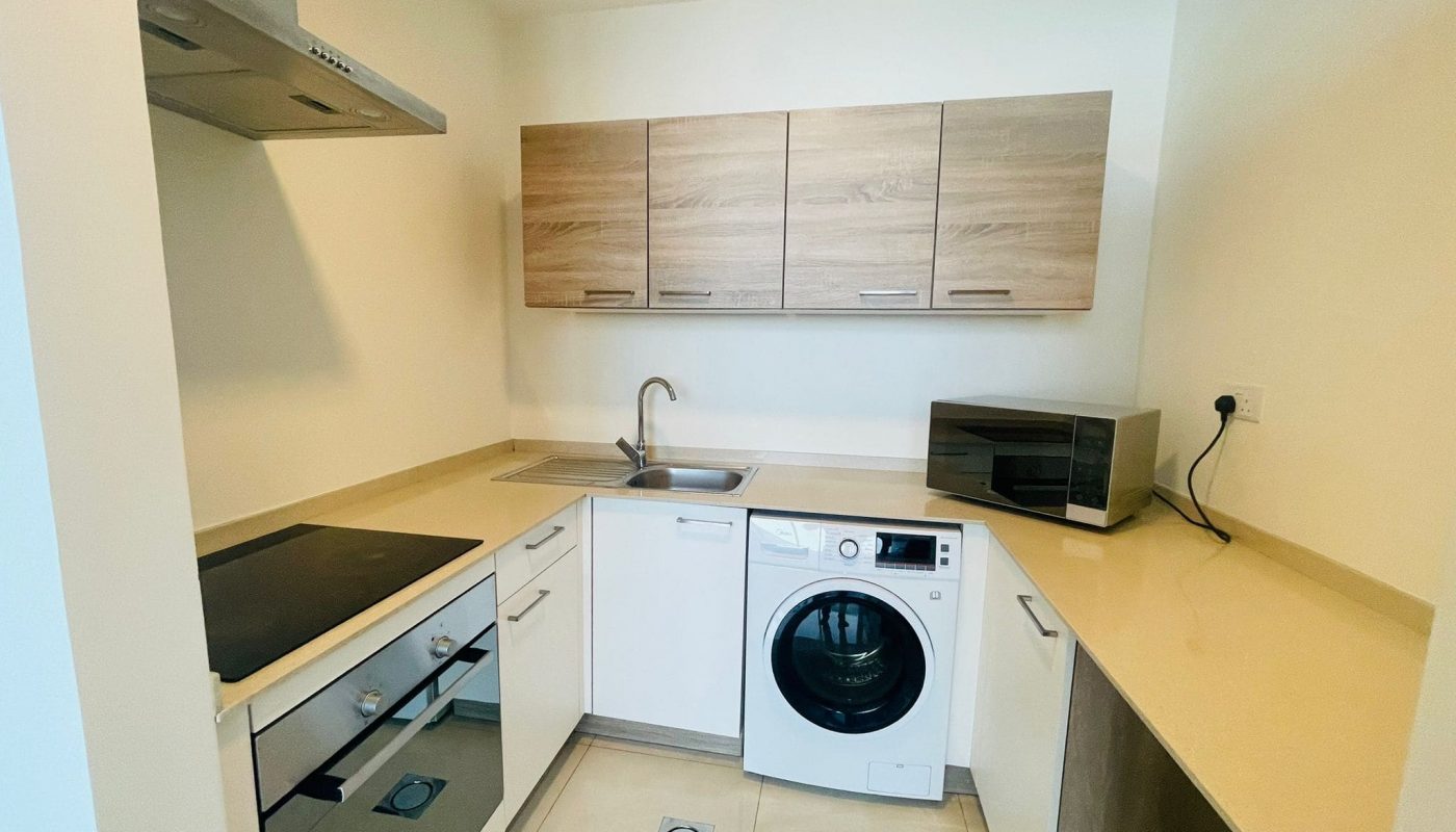 A luxurious 1 BR apartment in Juffair with a small kitchen equipped with a washer and dryer.