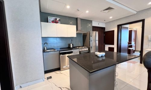 A luxury furnished flat in Juffair featuring a modern kitchen with marble counter tops and stainless steel appliances.