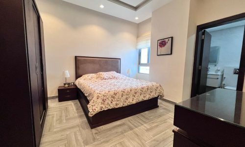 A luxury bedroom with a bed and a dresser in a fully furnished flat.