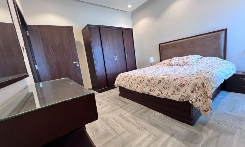 A luxury bedroom in Juffair fully furnished with a bed and a dresser.