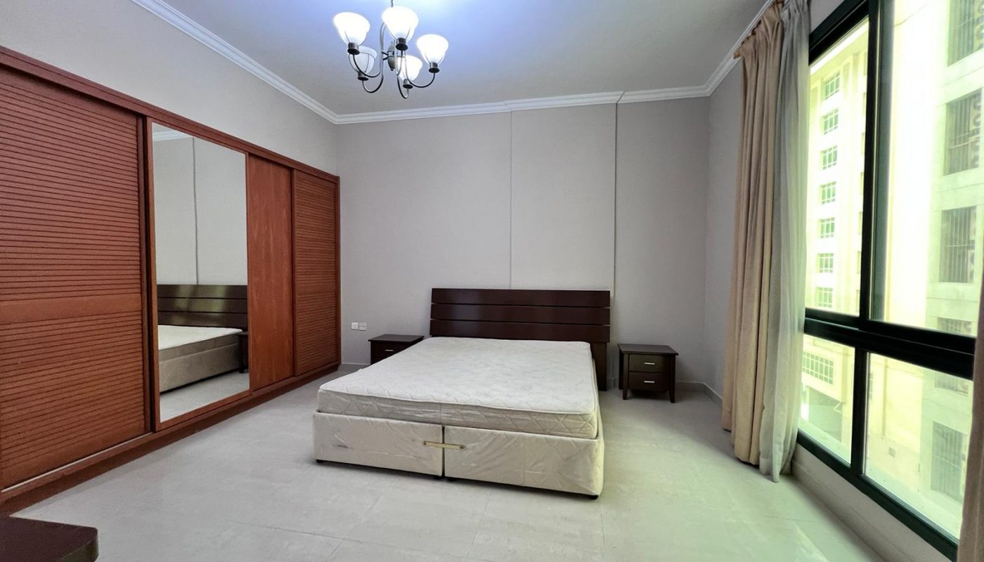 A bedroom with a bed, dresser and mirror.