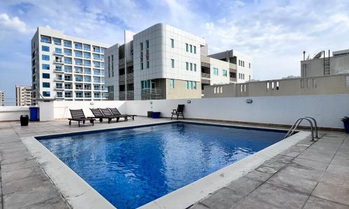 An apartment building featuring an auto-draft swimming pool centrally located.