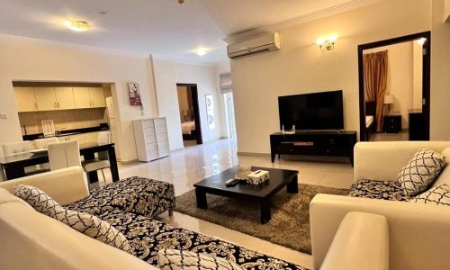 A living room with couches, coffee table and TV.