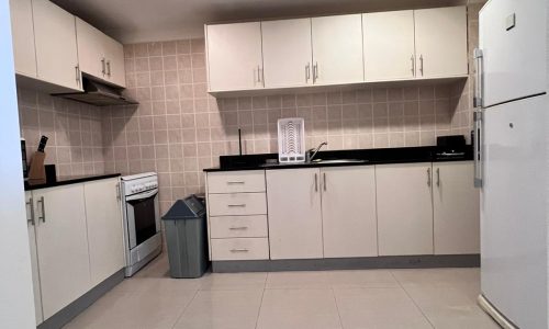 A kitchen with white cabinets and a refrigerator.