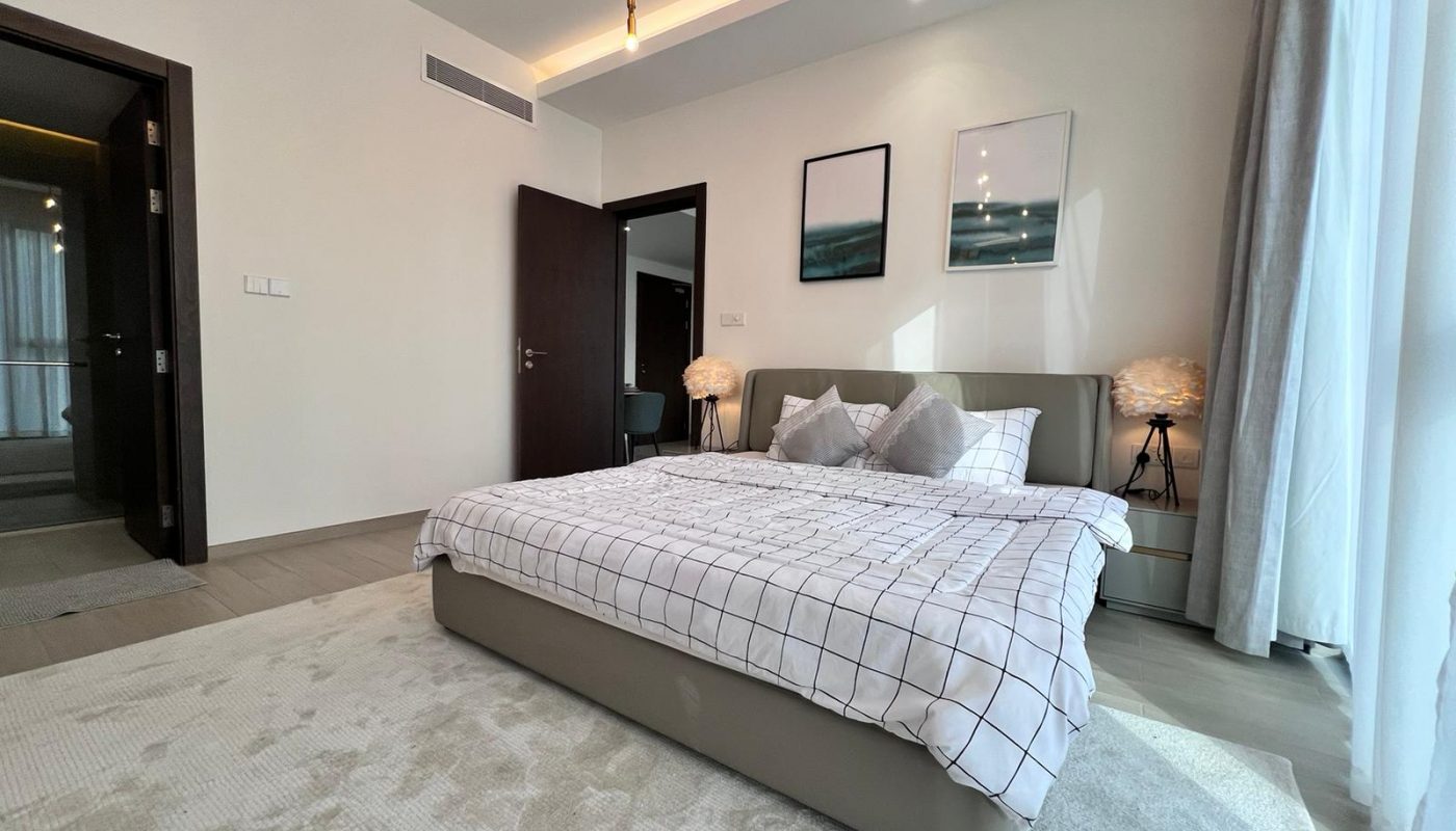 A modern bedroom with a bed and a bedside table in a luxury 1BR apartment located in Juffair.