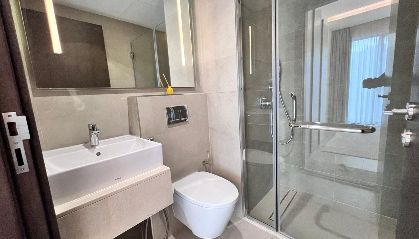 A luxury 1BR apartment in Juffair featuring a glass shower stall and toilet.