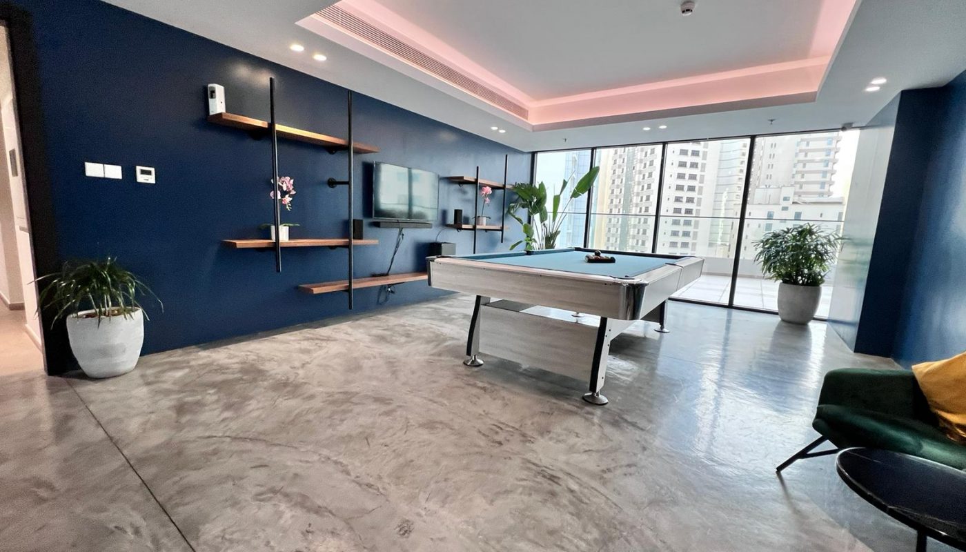 A luxury 1BR apartment in Juffair with a living room featuring a pool table and blue walls.