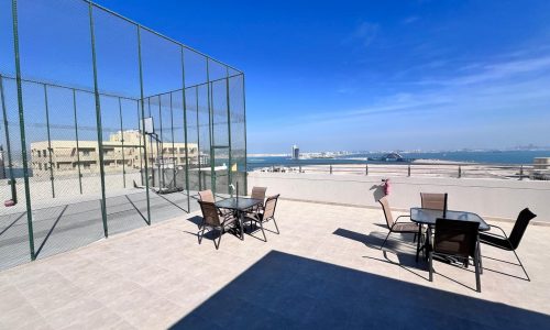 A Juffair apartment with a glass table and chairs overlooking the city, available for sale.