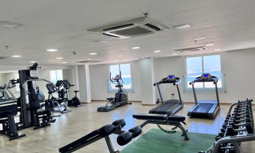 An apartment in Juffair for sale, featuring a gym room with tread machines and a fan.