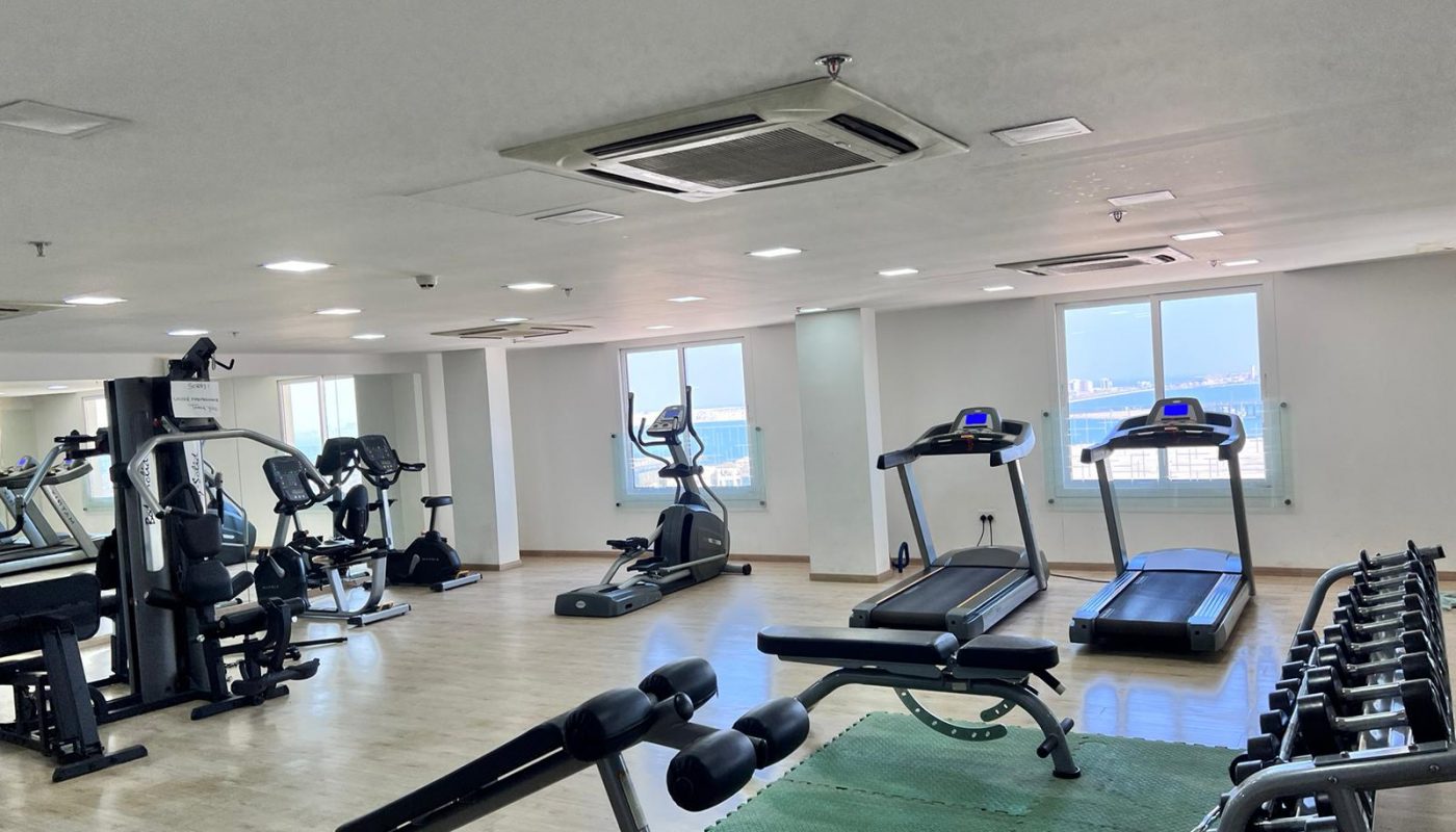 An apartment in Juffair for sale, featuring a gym room with tread machines and a fan.