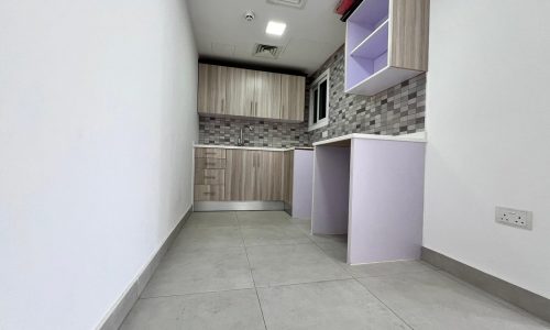 A small apartment in Juffair with a purple tiled floor and white cabinets is available for sale.