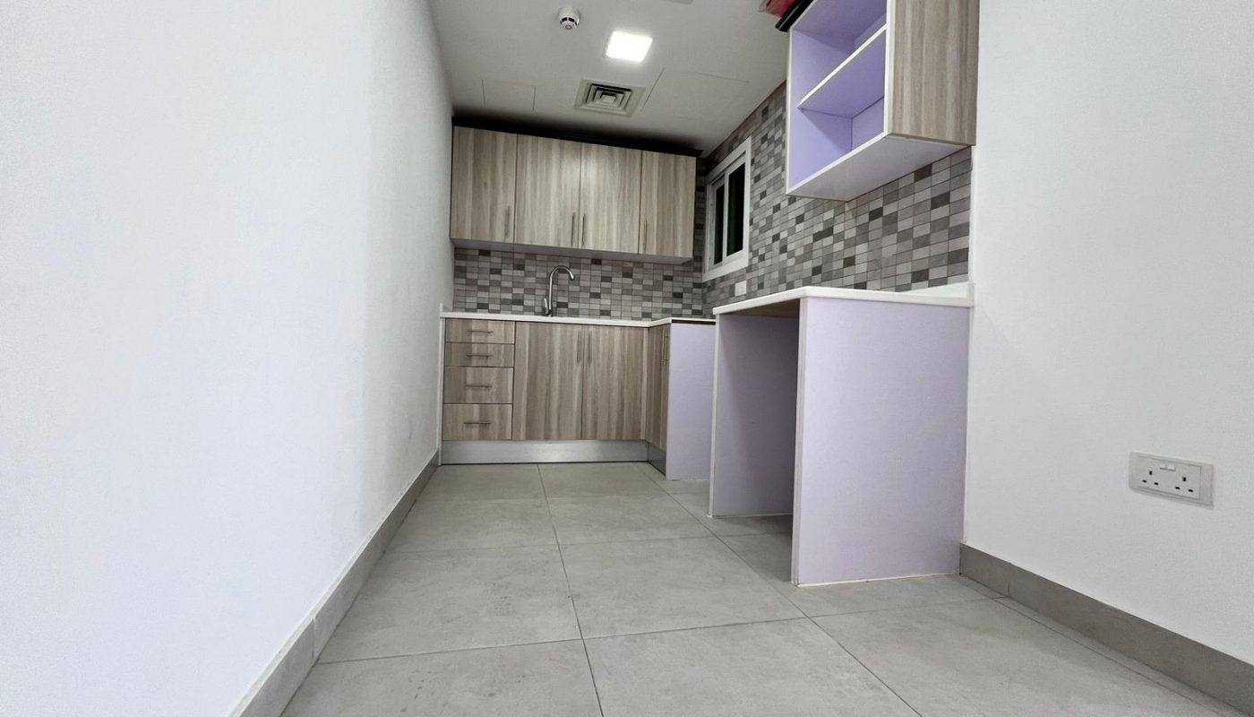 A small apartment in Juffair with a purple tiled floor and white cabinets is available for sale.