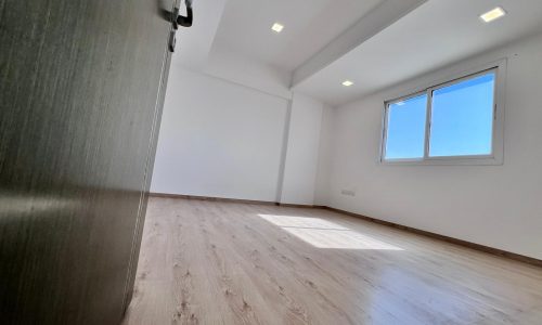 An empty apartment for sale in Juffair with wooden floors and a window.