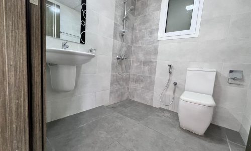 A Juffair apartment for sale with a bathroom featuring a toilet, sink, and shower.