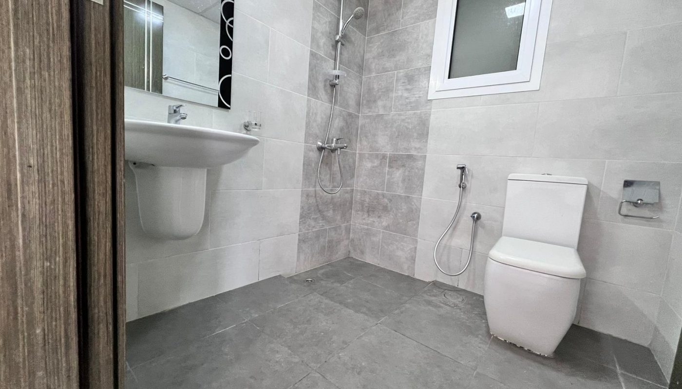 A Juffair apartment for sale with a bathroom featuring a toilet, sink, and shower.