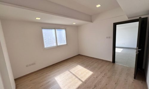 A Juffair apartment for sale, featuring an empty room with wooden floors and a window.