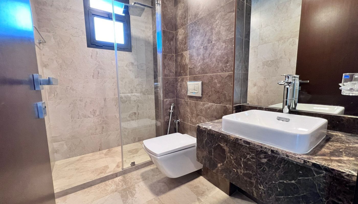 A luxury apartment with a bathroom featuring a toilet, sink, and shower.