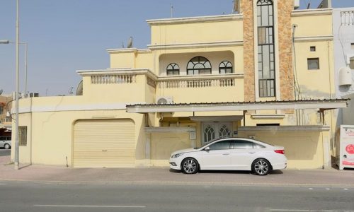 A large villa for sale in Isa Town with a car parked in front of it.