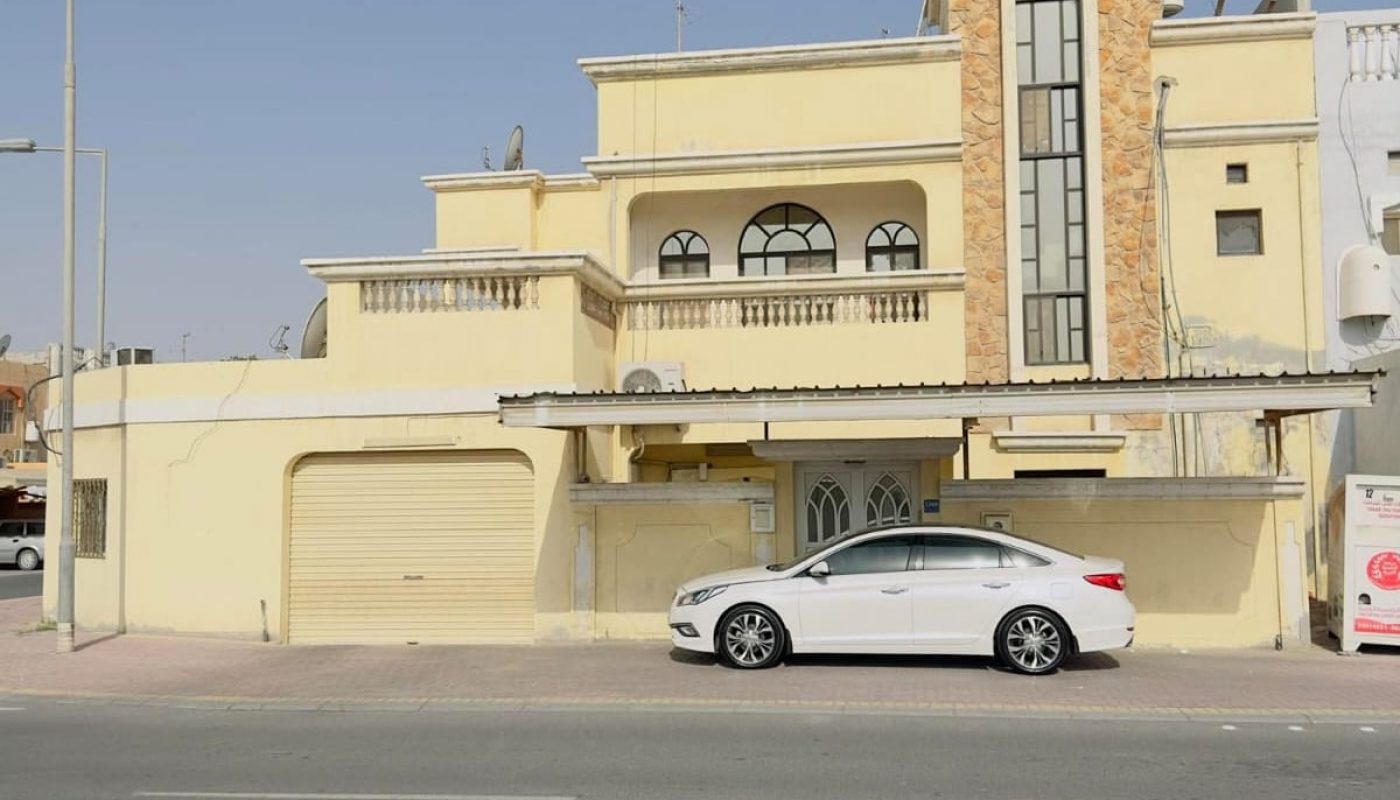 A large villa for sale in Isa Town with a car parked in front of it.