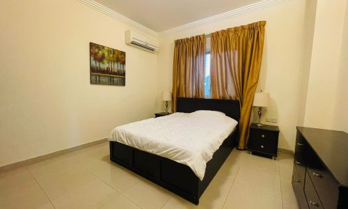 A Juffair bedroom with a bed and a dresser.