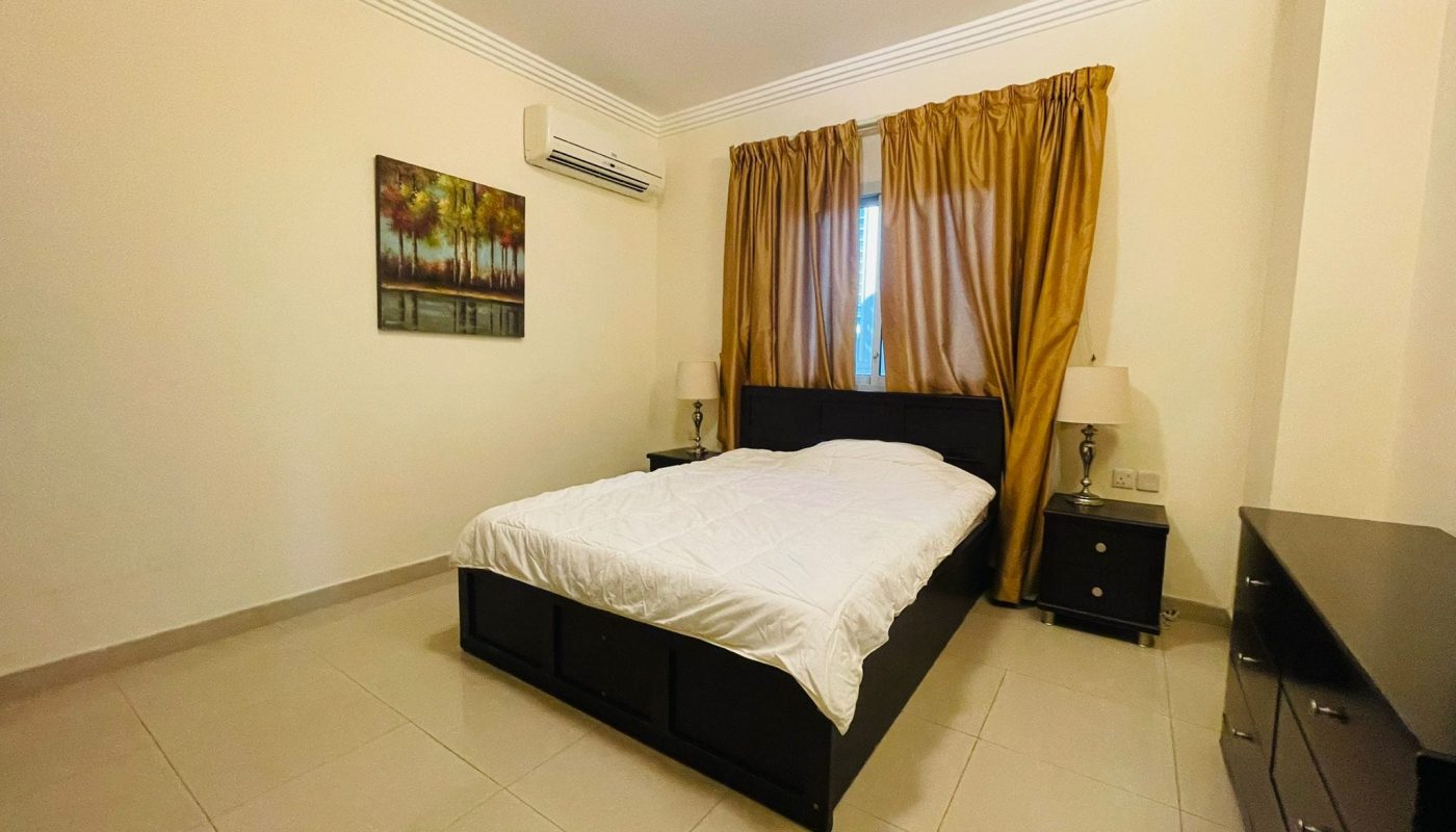 A Juffair bedroom with a bed and a dresser.