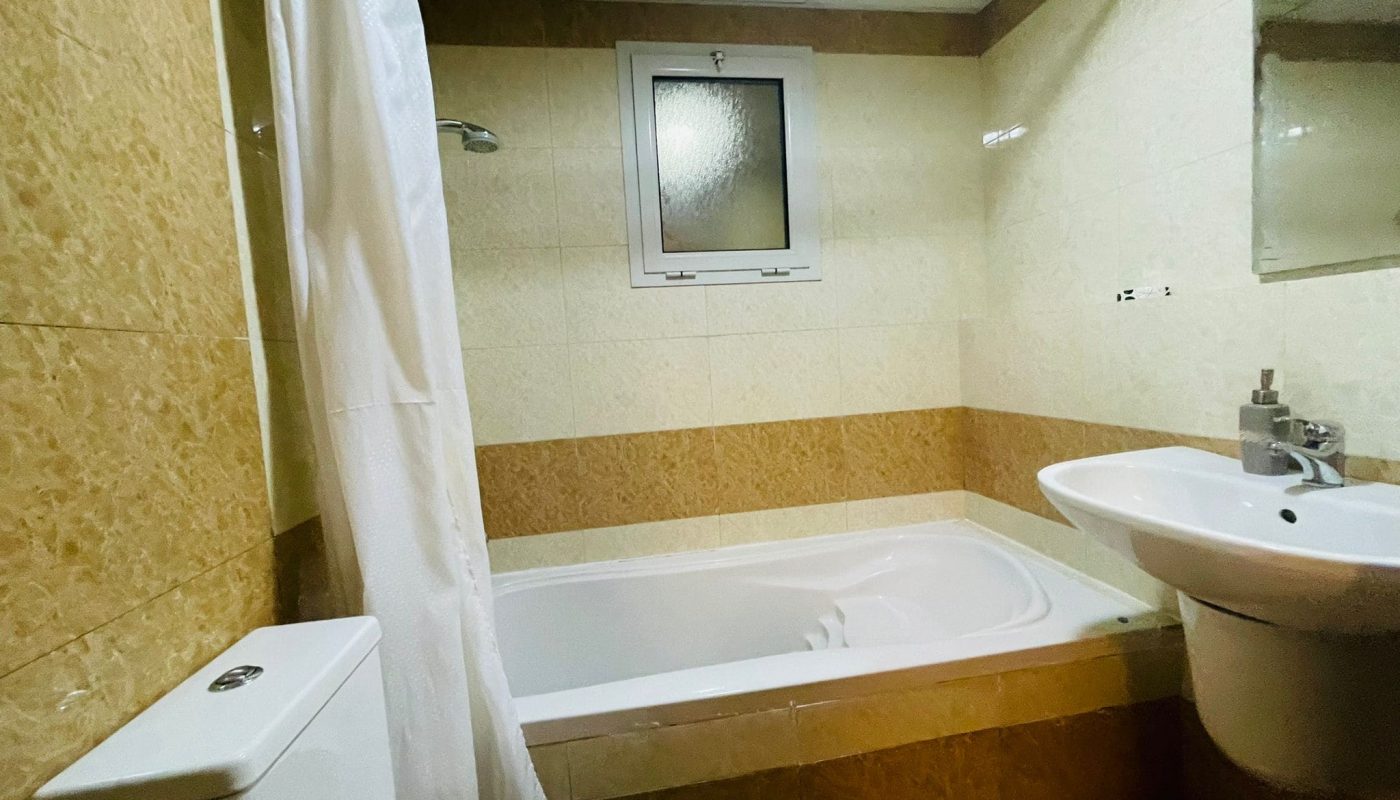 A Juffair apartment with a bathroom including a toilet, sink, and shower.