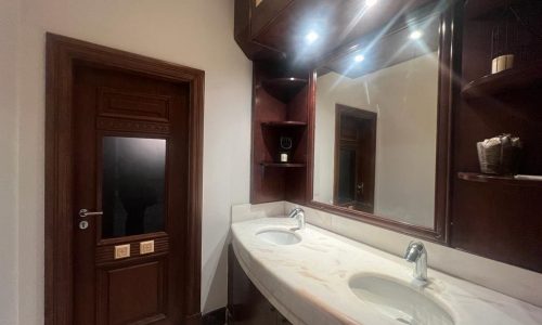 A Jufair villa for rent featuring two sinks and a mirror in the bathroom.